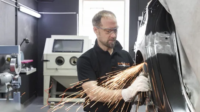 Karosseriebauer von STIMAC trennt mit der Flex ein Karosserieteil, Funken sprühen