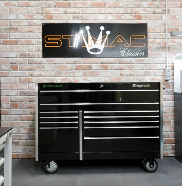Werkstattwand mit STIMAC-Classics-Schild über einem schwarzen Werkzeugwagen