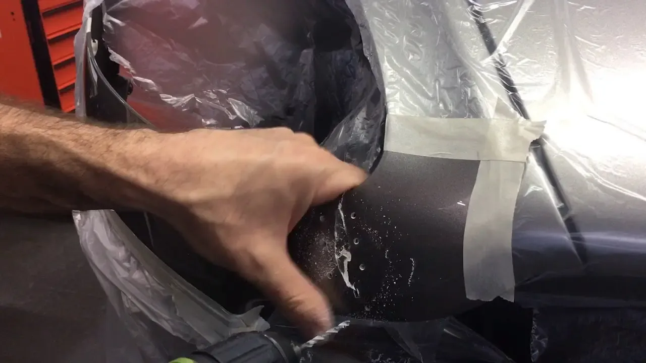 Hand bearbeitet ein abgeklebtes Karosserieteil eines Aston Martin