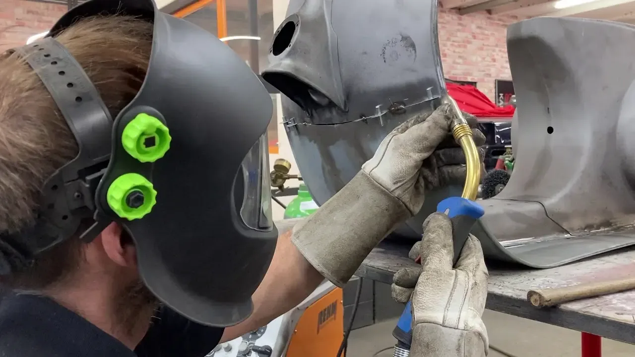 Mitarbeiter mit Schweißhelm schweißt an einem Blechteil einer Vespa V50